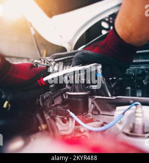 Auto mechanic repairing engine with socket wrench in the auto repair garage, automotive maintenance service concept Stock Photo