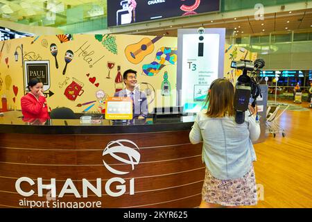SINGAPORE - NOVEMBER 03, 2015: woman with camera near information desk in Changi Airport. Singapore Changi Airport, is the primary civilian airport fo Stock Photo