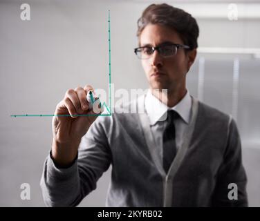 Presenting his business strategy. A young businessman writing on glass with a marker. Stock Photo