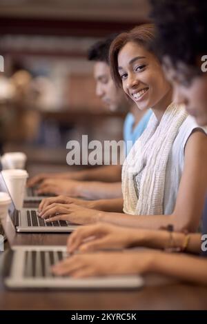 Working towards a bright future. A group of students using a laptop to complete a group assignment. Stock Photo