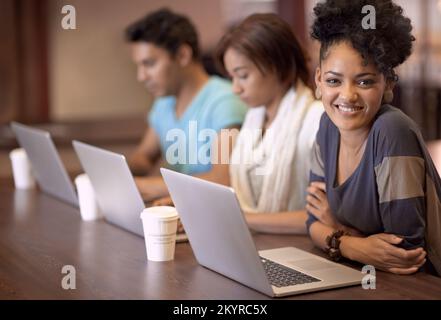 Working towards a bright future. A group of students using a laptop to complete a group assignment. Stock Photo