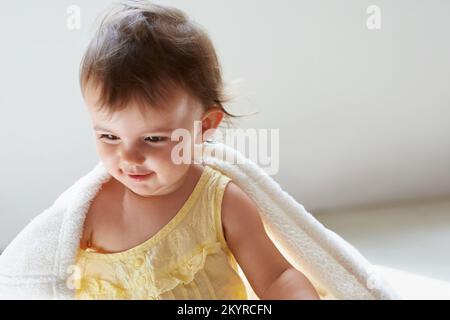 Such a pleasant little baby. a cute little baby girl sitting on the floor playing with her blanket. Stock Photo