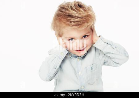 Hear no evil. A cute little boy covering his ears with his hands - isolated. Stock Photo