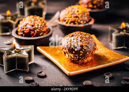 Small chocolate pastry cakes for Christmas with candles and ornaments Stock Photo