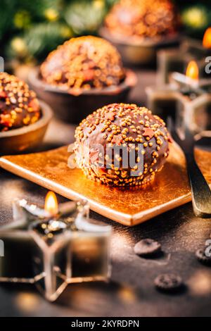 Small chocolate pastry cakes for Christmas with candles and ornaments Stock Photo