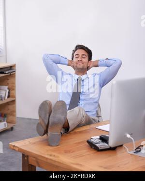 No stress. a handsome young businessman looking relaxed at his desk. Stock Photo