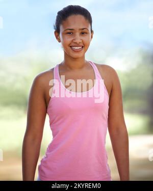 She loves being outdoors. A pretty young woman in sportswear exercising in the forest. Stock Photo