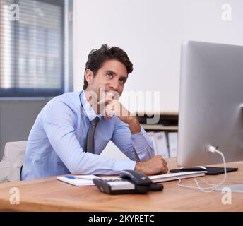 Imagining how bright his future is going to be. A handsome young businessman looking thoughtful in the office. Stock Photo