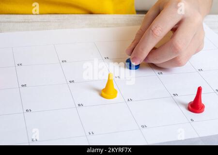Board game and children's leisure concept - a child's hand moves a game chip on the field. Multi-colored chips on a lined field. Minimalism. Family le Stock Photo