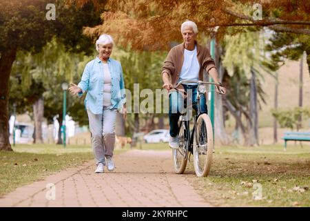 Senior couple, walking and bike at park, talking and bonding together mock up. Love, retirement and elderly man cycling on bicycle with happy woman Stock Photo