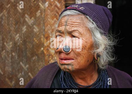 Ziro, Arunachal Pradesh, India - 02 24 2009 : Three quarter portrait of old Apatani tribal woman with traditional facial tattoos and nose plugs Stock Photo