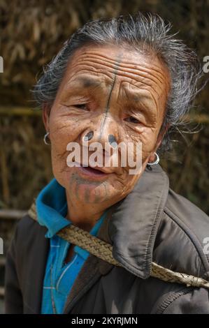 Ziro, Arunachal Pradesh, India - 03 04 2014 : Portrait of old Apatani tribal woman with traditional facial tattoos and nose plugs walking in village Stock Photo