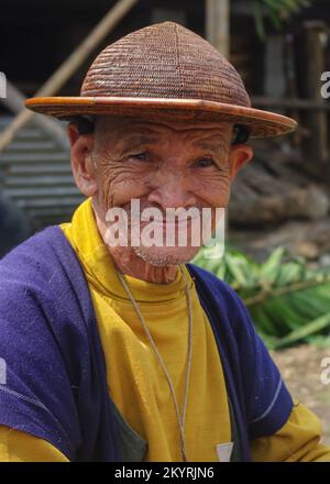 West Siang, Arunachal Pradesh, India - 03 06 2014 : Portrait of smiling old Adi Galong or Galo tribe man wearing traditional boat shaped cane hat Stock Photo