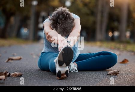 Fitness, senior and woman stretching legs outdoors for wellness, flexibility and mobility. Health, retirement and elderly female doing warm up Stock Photo