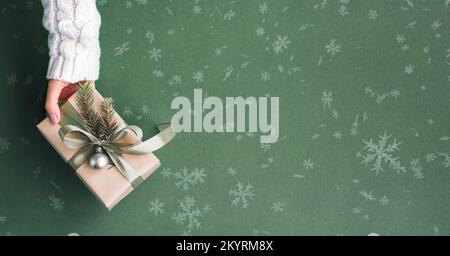 Female hands holding Christmas gift box on pastel green background. Stock Photo