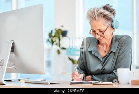 Senior woman, headphones and writing in office or happy planning motivation with notebook and music. Elderly person, smile and business happiness Stock Photo