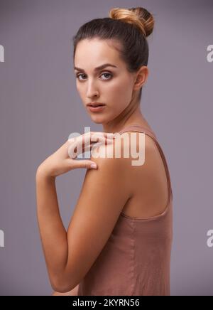 Effortlessly beautiful. An attractive young woman against a purple background. Stock Photo