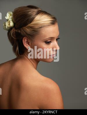 Elegance and natural beauty. Rearview studio shot of an attractive young woman with a flower in her hair. Stock Photo