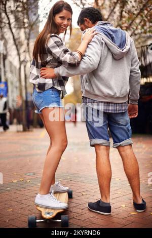 Balance is everything. a young man teaching his girlfriend how to skateboard. Stock Photo