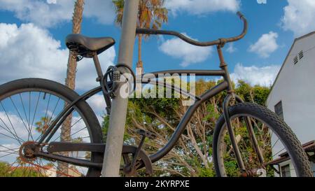 Panorama White puffy clouds Bicycle locked on a metal pole at La Jolla, California. Parked black bicycle on a lawn with cable lock against the view of Stock Photo