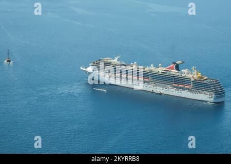 Santorini, Greece - September 16, 2022 : View of a cruise liner next to a small boat in Santorini Greece Stock Photo