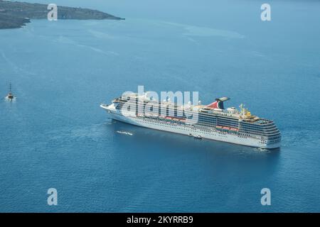 Santorini, Greece - September 16, 2022 : View of a cruise liner next to a small boat in Santorini Greece Stock Photo