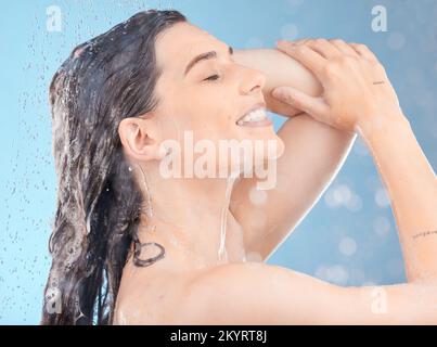 Shower, cleaning and woman with water for hair in studio for skincare, body care and wellness on blue background. Self care, hydration and girl Stock Photo