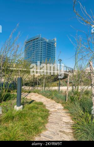 Walking trail on grassy land at Waterloo Park in Austin Texas on a sunny day. Stone brick pathway with elevated boardwalk and buildings against blue s Stock Photo