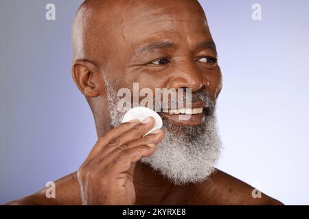 Face, skincare and antiaging with a senior black man exfoliating his skin in studio on a gray background. Beauty, cleaning and cleansing with a mature Stock Photo