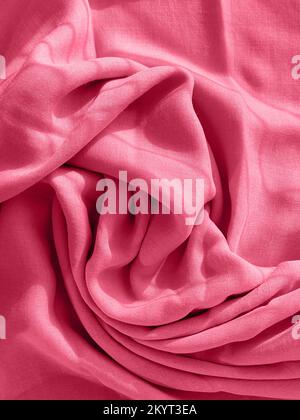 Stylish folded fabric with lovely waves, texture and pattern. Photo toned in color of the year 2023 viva magenta. Stock Photo