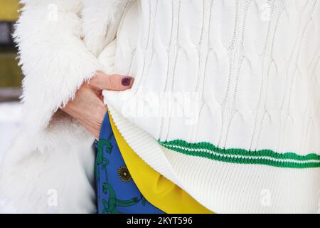 Close up hand in pocket of fashionable aged woman in white clothes, knitted sweater with colorful accents, winter style, fashion detail Stock Photo