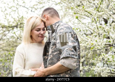 Soldier reunited with wife in park. Stock Photo