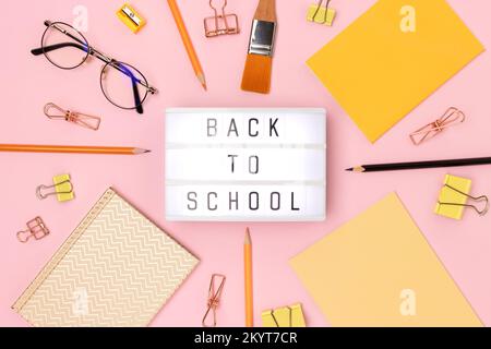 Back to school. Lightbox with letters and frame made of stationery on a pink background. Stock Photo
