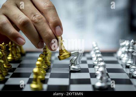 Close up of hands of a business man moving king golden chess to defeat  opponent the chess game is development analysis, strategy, and plan, the  management or leadership concept. 22804709 Stock Photo