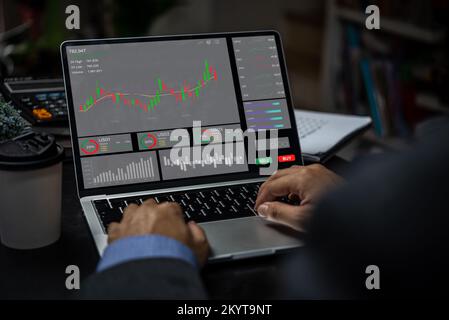 Businessman trader looking on laptop with graphs analysis candle line report stock market diagram profit. Stock Photo