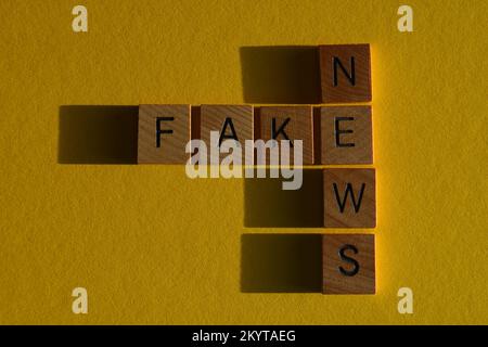 Fake News, words in wooden alphabet letters in crossword form isolated on yellow background Stock Photo