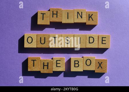 Think Outside The Box, words in wooden alphabet letters isolated on purple background Stock Photo