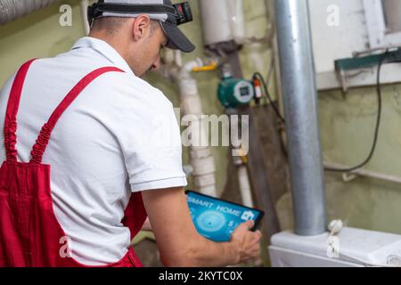 The technician checking the heating system in the boiler room with tablet in hand. Stock Photo