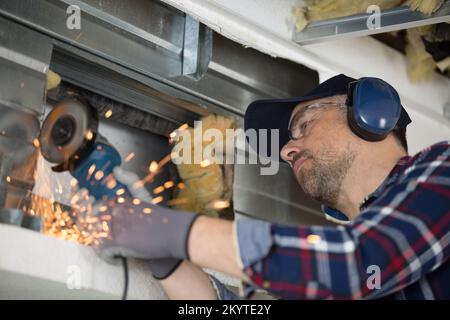 a window fitter using a disc cutter on brickwork Stock Photo
