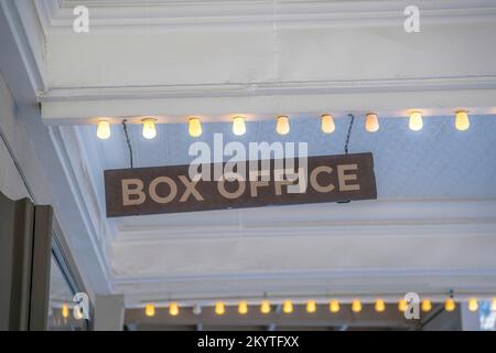Hanging Box Office signage on a ceiling with row of light bulbs. Uneven hanging signage against the white wooden ceiling at the background. Stock Photo