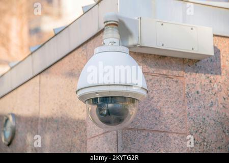 Austin, Texas- Close-up of a dome CCTV at the corner of a building. Surveillance camera against the granite wall cladding of the building. Stock Photo