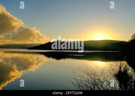 Late afternoon winter sun and clouds over the still, glassy waters of Slapton Ley, Start Bay, South Devon, UK Stock Photo