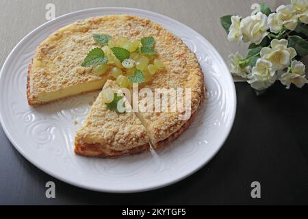 Round cottage cheese casserole decorated with fresh grapes and mint on a white plate. Fresh baked homemade cottage cheese casserole. Healthy food, bab Stock Photo