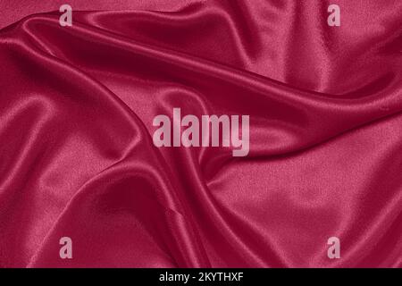 Texture of crumpled satin fabric, color of the year 2023 Viva Magenta Stock Photo