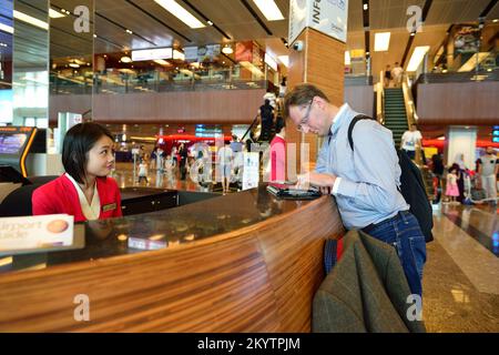SINGAPORE - NOVEMBER 07, 2015: passenger near information desk at Changi airport. Singapore Changi Airport, is the primary civilian airport for Singap Stock Photo