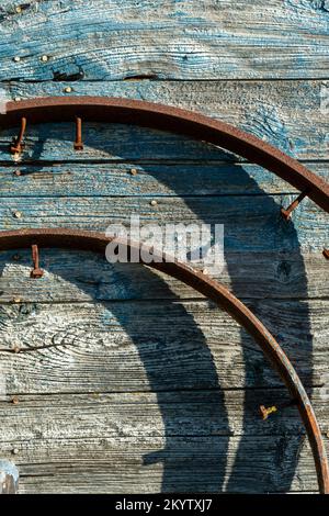 Vertical shot of rustic metallic pieces with nails on a grunge wooden surface Stock Photo