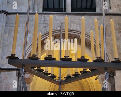 Close up of fresh new candle sticks seen in a black stand in the interior of a church building. Stock Photo