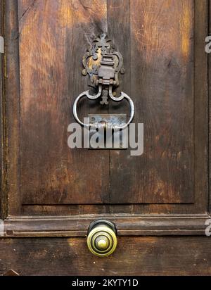 Intricate wooden door with vintage knocker and golden doorknob Stock Photo