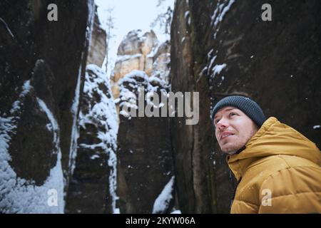 Portrat of man in the middle of snowy rocks during winter frosty day. Stock Photo