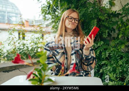 Stressed young caucasian woman having problem with not working smartphone or tablet in coffee shop cafe. Unhappy worried freelance working woman Stock Photo